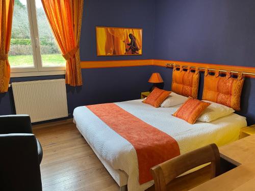 a bedroom with a large bed with an orange blanket at Logis Hôtel L'Adourable Auberge in Soublecause