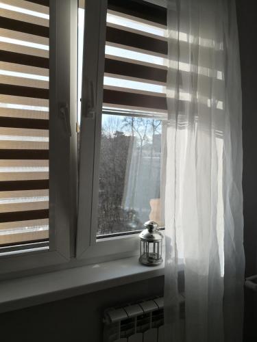a window with a white curtain and a candle at Różowe sny in Kłodzko