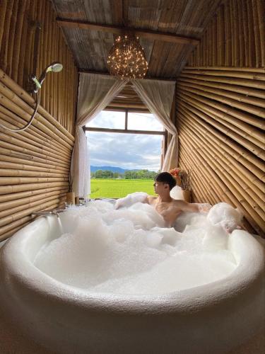 a man sitting in a bath tub with a window at ต้งโฮมสเตย์ กลางทุ่งนา Local Homestay and View in Nan