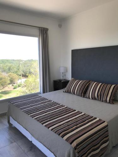 1 dormitorio con 1 cama grande y ventana grande en Aparts del lago de los cisnes en Necochea