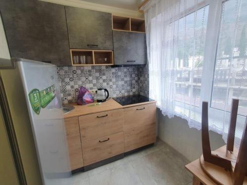uma pequena cozinha com um frigorífico e uma janela em Квартира em Gagra