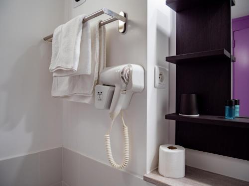 a white phone is hanging on a wall in a bathroom at Contact Hotel Restaurant La Chaumière entre Orgeval et Flins A13 sortie 8 in Les Mureaux