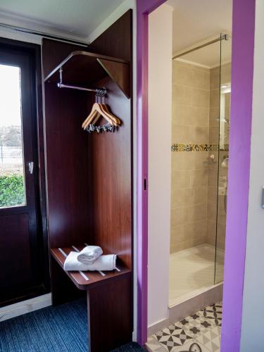 a bathroom with a walk in shower next to a wooden door at Contact Hotel Restaurant La Chaumière entre Orgeval et Flins A13 sortie 8 in Les Mureaux