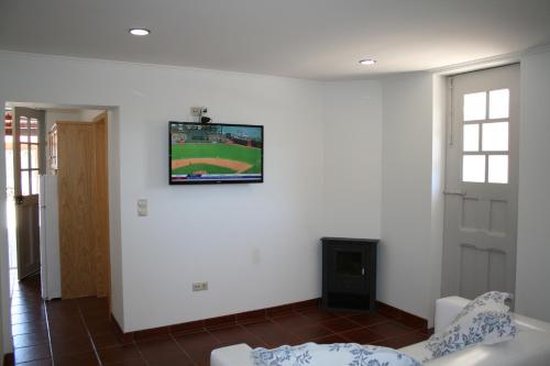 ein Wohnzimmer mit einem an der Wand hängenden TV in der Unterkunft Murtosa House in Torreira