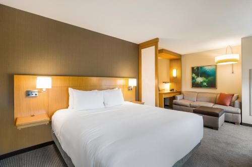 a hotel room with a large bed and a couch at Hyatt Place Hampton Convention Center in Hampton