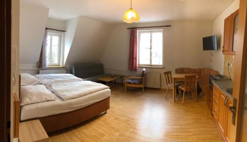 a bedroom with a bed and a table and a kitchen at Penzion Dubík in Dubí