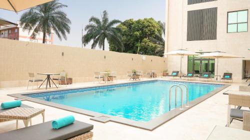 une piscine avec des tables et des chaises dans un hôtel dans l'établissement STAR LAND HOTEL BASTOS, à Yaoundé
