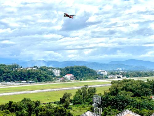 an airplane flying in the sky over an airport at AruSuites Tanjung Aru Kota Kinabalu By LAXZONE in Kota Kinabalu