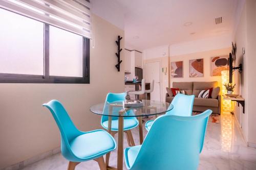 a dining room with blue chairs and a glass table at Slava Luxury Suite in Seville