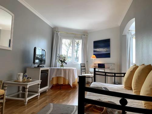 a living room with a couch and a table with a tv at Hôtel Causse Comtal Rodez, The Originals Relais in Gages-le-Haut