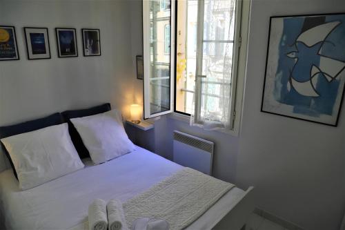 une chambre avec un lit avec des draps blancs et une fenêtre dans l'établissement Hoche Cannes Centre 