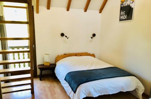 a small bedroom with a bed with a blue blanket at Gîte La Grange au Bois in Viella