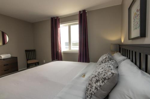 a bedroom with a large white bed with a window at The Killick Inn & Suites in Arnold's Cove