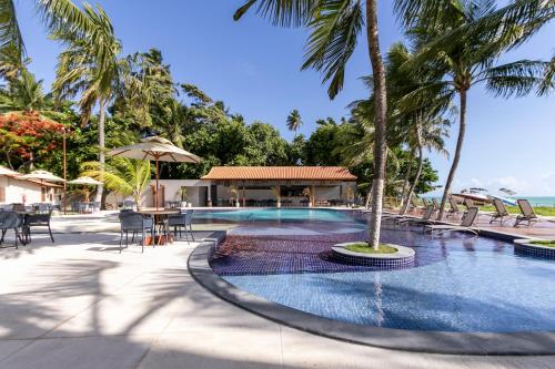 a pool at a resort with palm trees at Costa Dourada Village in Maragogi