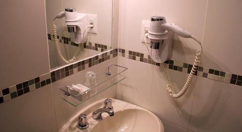 a bathroom with a sink and two hair dryers at Plaza Hotel Fray Bentos in Fray Bentos