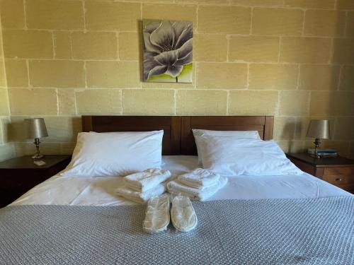 a bed with two pairs of slippers on it at Gilju B&B in Tal-Barmil