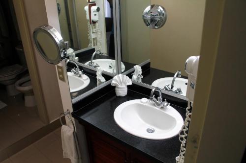 un bagno con due lavandini e un grande specchio di HOTEL ALTAMIRA SUITES a Caracas