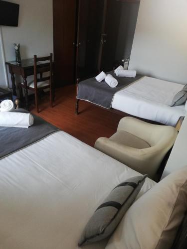 a hotel room with two beds and a chair at Hotel Termas in Chaves