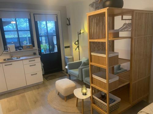 a living room with a book shelf and a kitchen at Vakantiehuisje het kiekje in Bergen op Zoom
