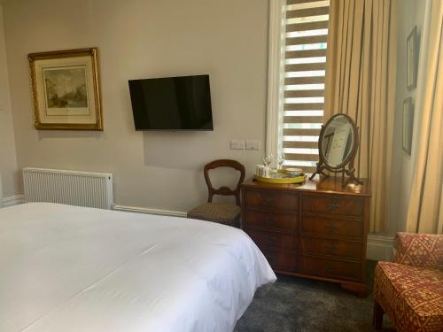 a bedroom with a bed and a dresser and a television at The Gaydon in Lytham St Annes