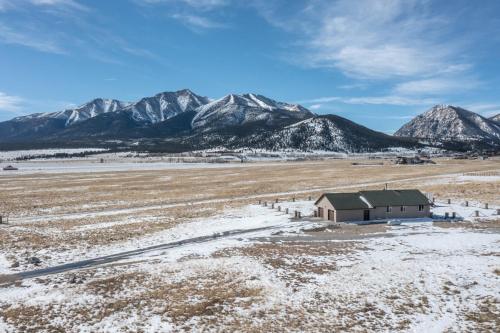 a barn in a field with mountains in the background at Buena Vista Mountain Retreat - Ultimate Privacy with Spa & Unbeatable Views in Buena Vista