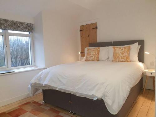 a bedroom with a large bed with white sheets and pillows at No8 3 bed cottage Winter Deals offered 3 nights or more Nov-Mar in Backbarrow
