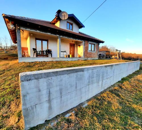 una pequeña casa detrás de una pared de hormigón en Kuća na dan Vrla strana en Bosansko Petrovo Selo