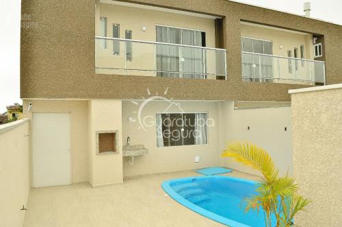 una casa con piscina frente a ella en Sobrado PôrDoSol2 Aconchegante 4 suítes pertodomar, en Guaratuba