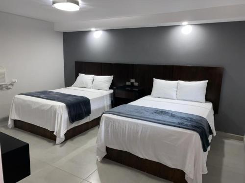 a bedroom with two beds with white sheets at Hotel Senorial in Puerto Peñasco