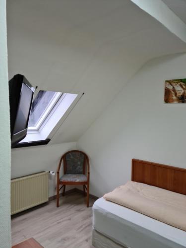 a bedroom with a bed and a window and a chair at Pension Kreihe im Harz in Bad Lauterberg