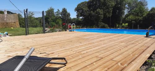 een groot houten terras naast een zwembad bij Les gîtes de la commanderie de Saint Jean SCAFER in Beynat