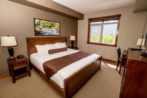 1 dormitorio con cama, escritorio y ventana en Spacious Penthouse Suite-king Beds-pool & Hot Tub, en Canmore