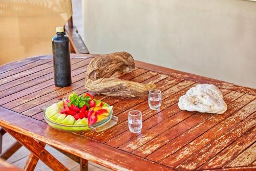 a wooden table with a bowl of fruit and a bottle at Ulivo Sea View House in Kokkíni Khánion