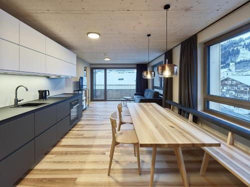 a kitchen and dining room with a wooden table and chairs at DER*ADLER Apartments in Schoppernau
