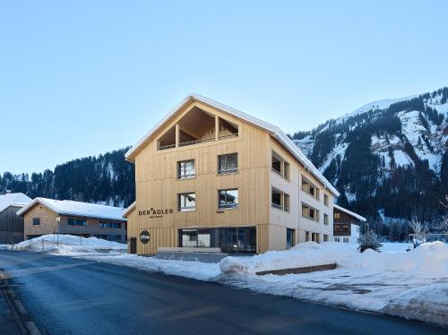 a large building on the side of a snow covered road at DER*ADLER Apartments in Schoppernau