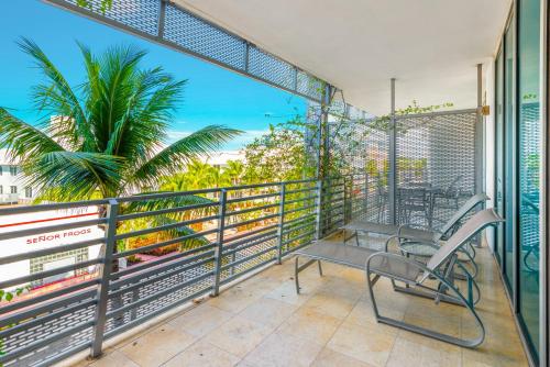 a balcony with a chair and a palm tree at Luxury Balcony Suite - Across the Beach and Espanola Way in Miami Beach