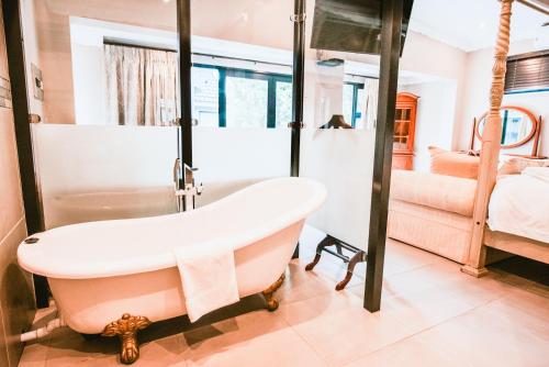 a bathroom with a bath tub and a bedroom at Le Grant Guesthhouse in Kroonstad