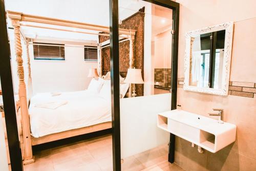 a bathroom with a bed and a sink and a mirror at Le Grant Guesthhouse in Kroonstad