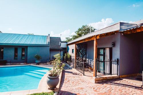 a house with a swimming pool next to a building at Le Grant Guesthhouse in Kroonstad