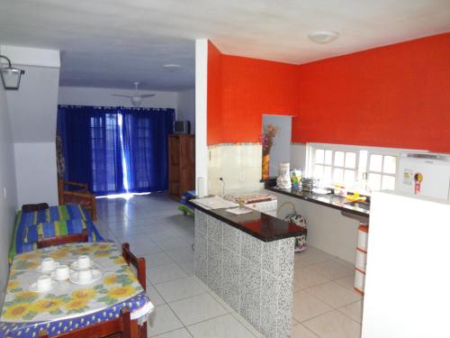 a kitchen with red walls and a table and a dining room at Flats Paraty in Paraty