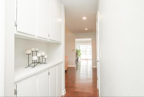 a white kitchen with white cabinets and a hallway at Valencia CA Stunning 3100 +sqft, 5Bed/5Bath home in Santa Clarita