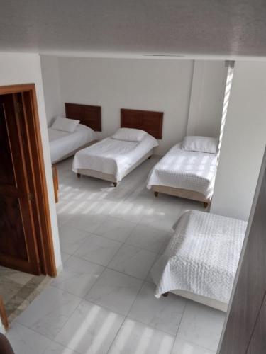 a room with three beds and a mirror at HOTEL ZUHE in Paipa