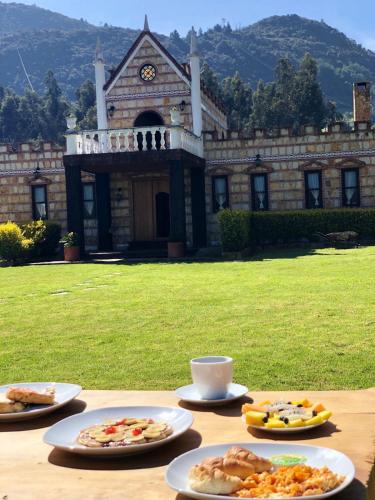 a table with plates of food on it in front of a building at Castillo Casablanca in Guatavita