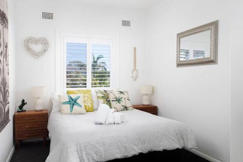a white bedroom with a bed and a window at Moana Blue in Shoal Bay