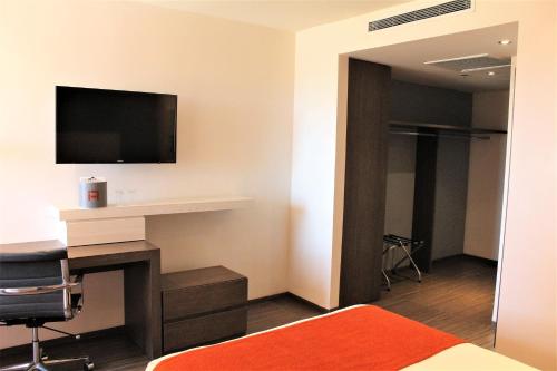 a hotel room with a desk and a tv on the wall at Real Inn Cancún in Cancún