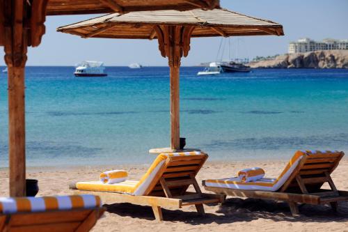 two lounge chairs and an umbrella on a beach at Naama Bay Promenade Beach Resort Managed By Accor in Sharm El Sheikh