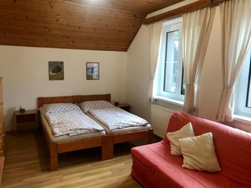 1 Schlafzimmer mit 2 Betten und einem roten Sofa in der Unterkunft Chalupa Václav Lipno in Lipno nad Vltavou