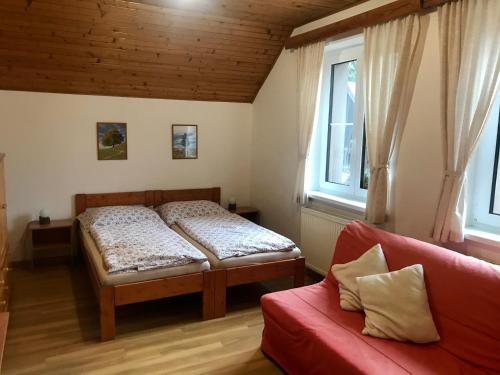リプノ・ナト・ヴルタヴォウにあるChalupa Václav Lipnoのベッドルーム1室(ベッド2台、赤いソファ付)