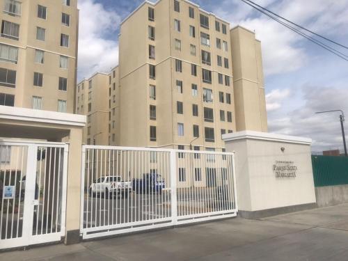 a white gate in front of a tall building at Departamento de estreno en 1er piso en Condominio in Piura