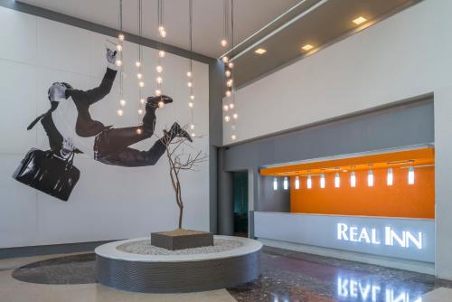 a lobby with a sculpture of two women and a tree at Real Inn Nuevo Laredo in Nuevo Laredo